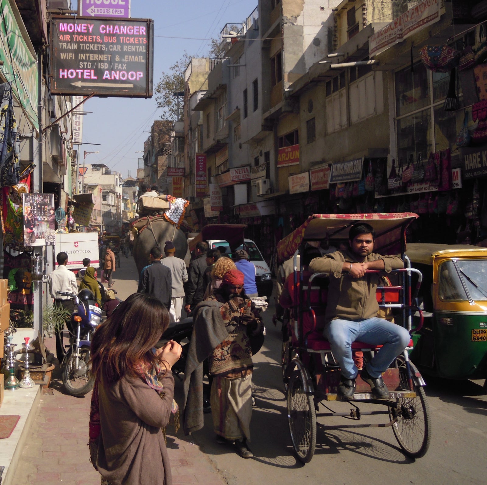 Many different modes of transportation on a busy street in Delhi including an elephant!