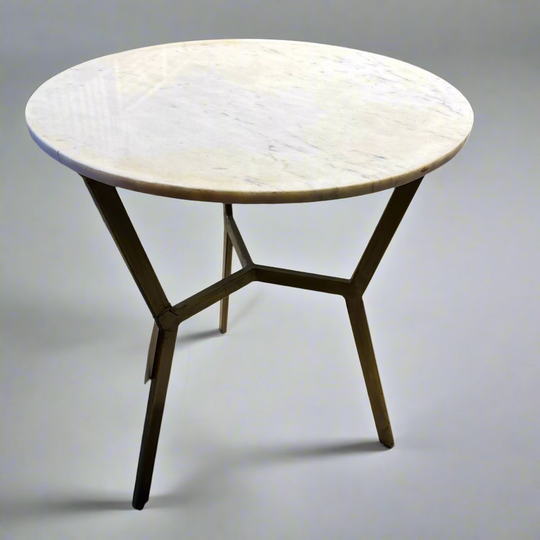 Round marble table with metal legs on a concrete floor