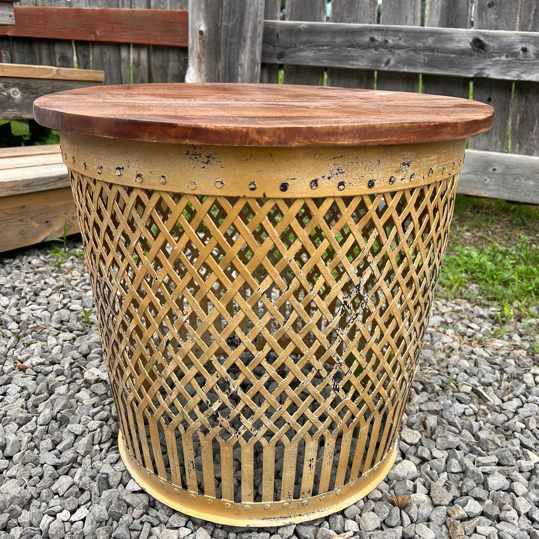 iron side table with wooden top on a gravel surface