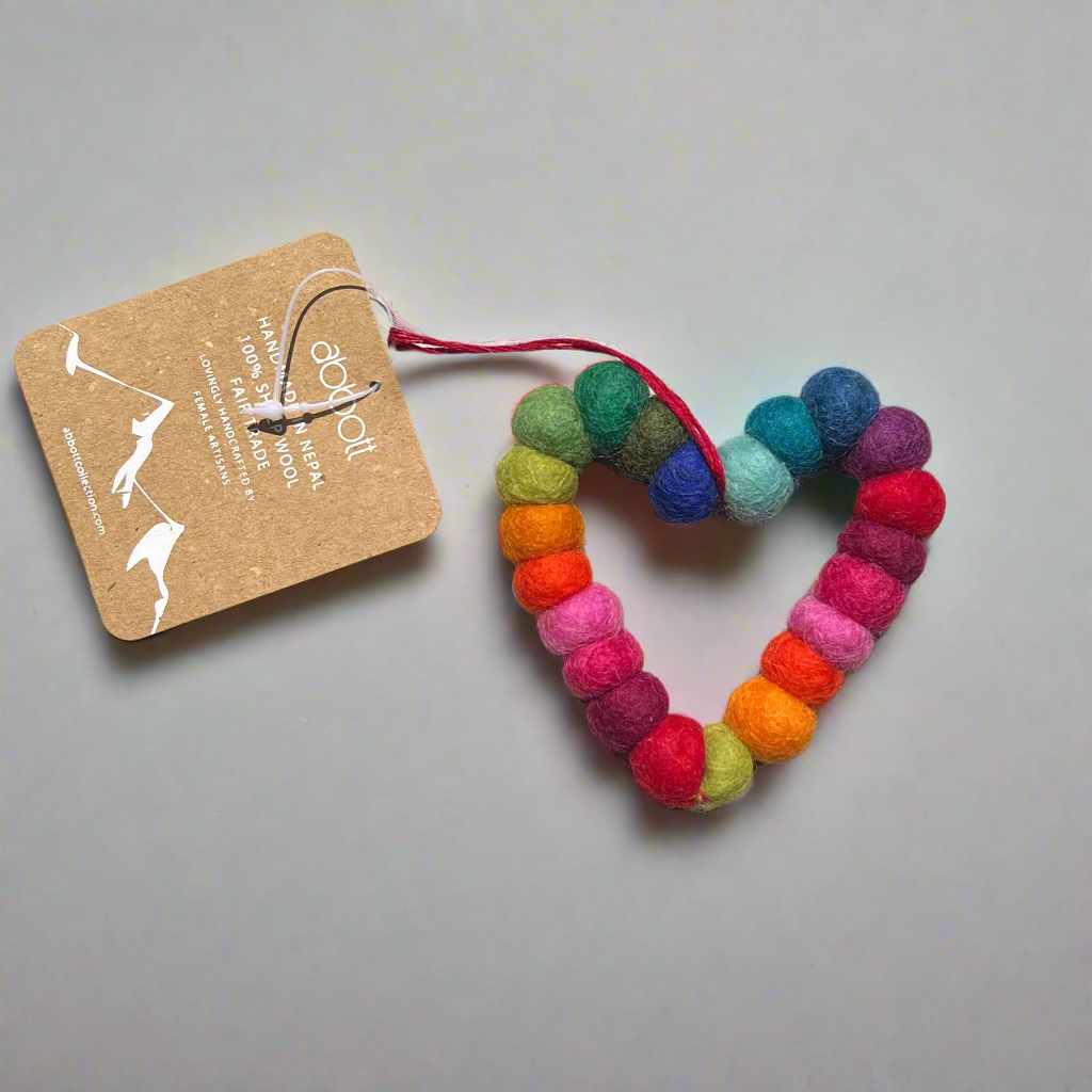 Colorful heart-shaped felt ornament with a tag on a textured surface
