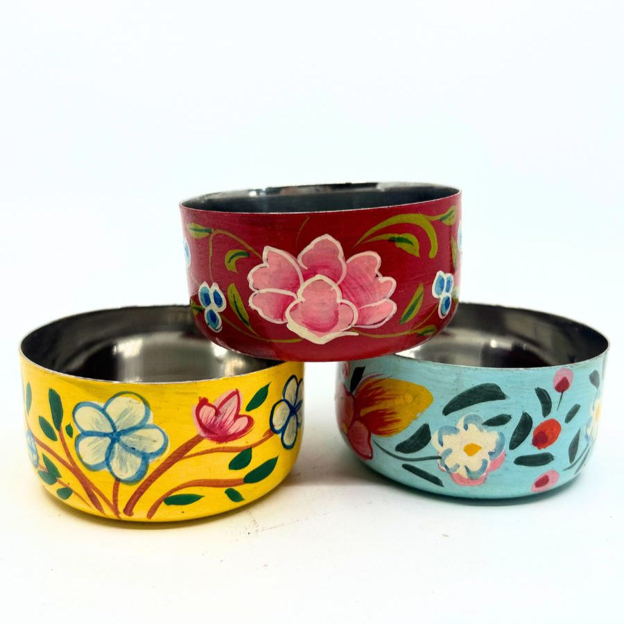 A set of three stainless steel hand painted bowls with traditional Rajasthani style floral patterns in red, yellow, and blue colors.