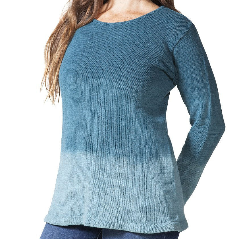 A woman wearing a blue ombre pullover with long sleeves, made of knit cotton, standing against a neutral background.