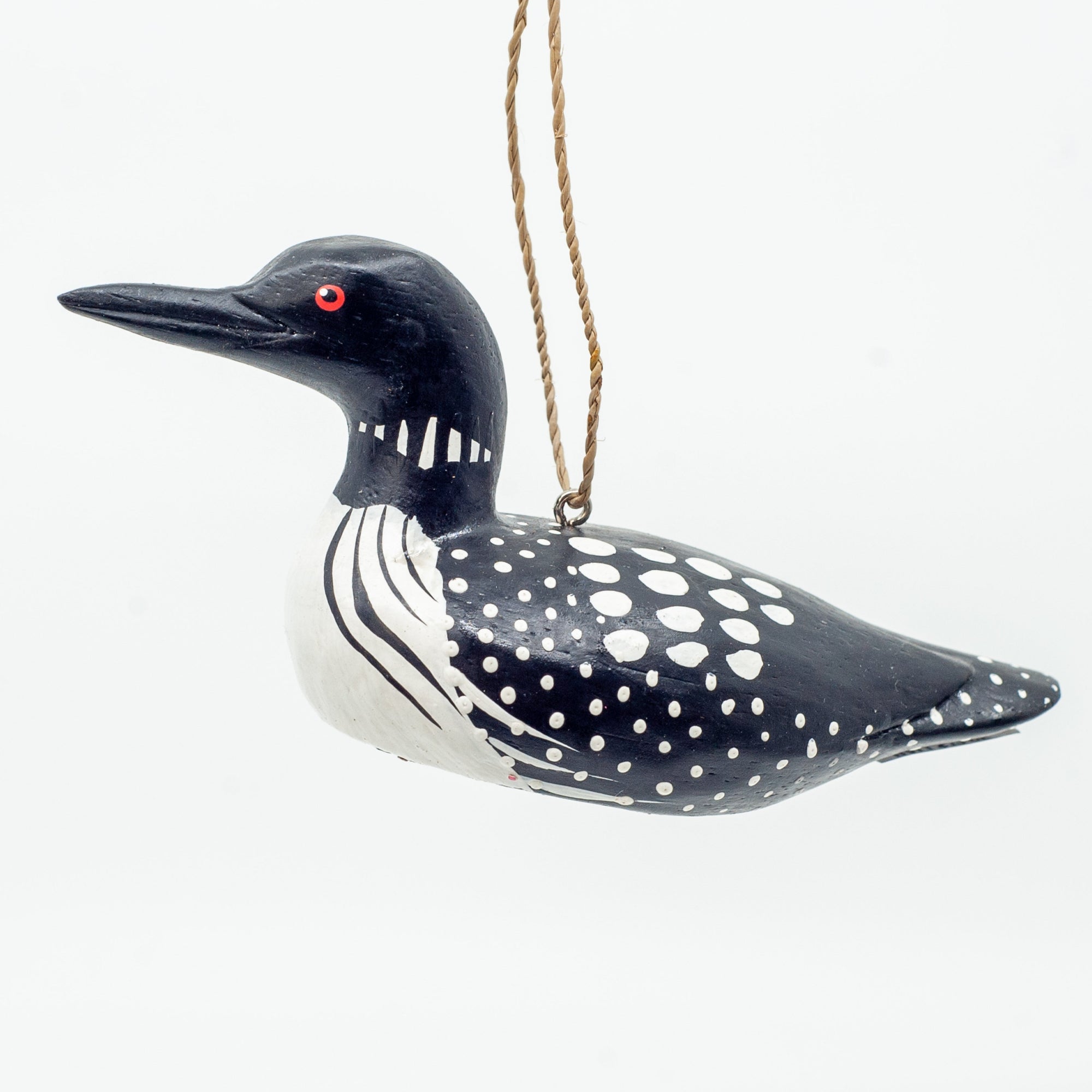 Small wooden loon ornament on white background hanging from string. 