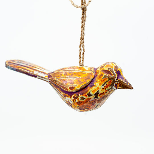 Small driftwood bird ornament on white background hanging from string.