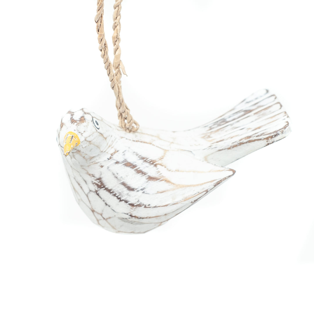Small driftwood bird ornament on white background hanging from string.
