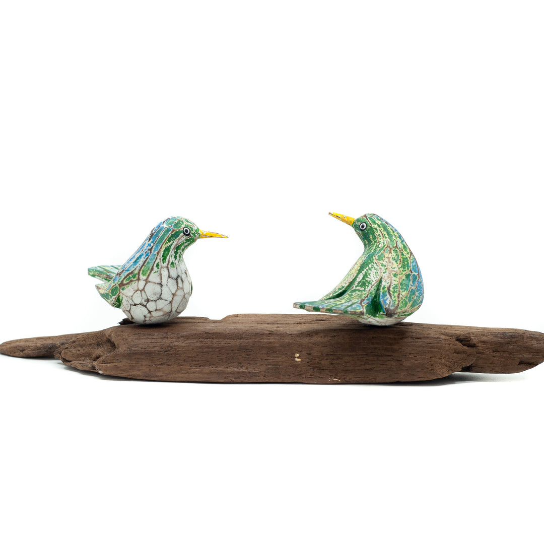 Small driftwood birds on white background on wooden base.