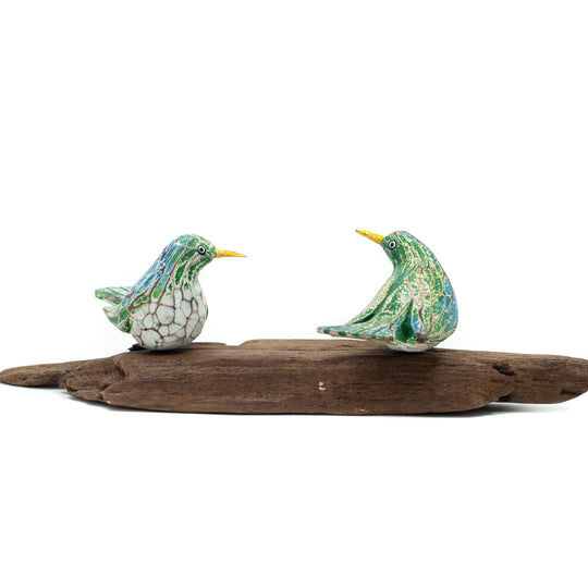 Small driftwood birds on white background on wooden base.
