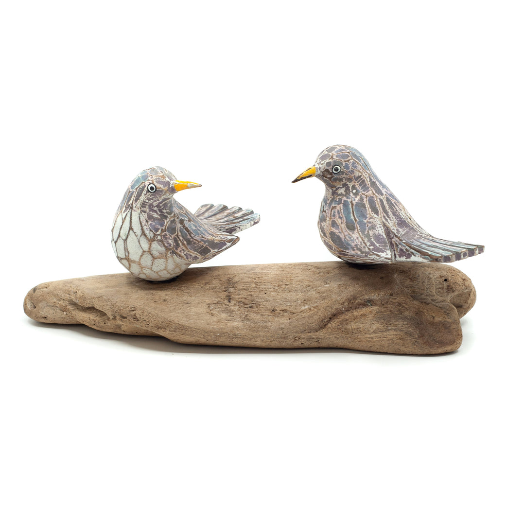Small driftwood birds on white background on wooden base.