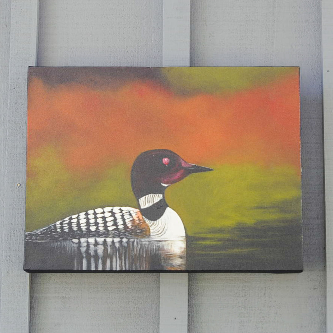 Loon on calm water with fall colours