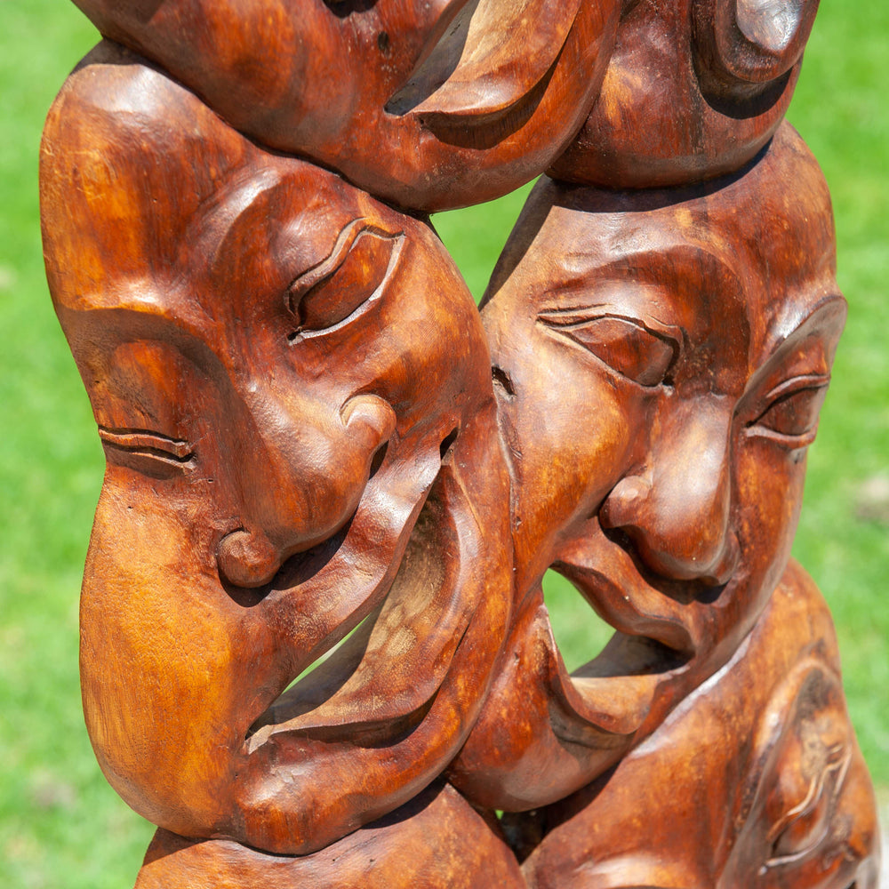 A unique wooden carved statue featuring many laughing faces