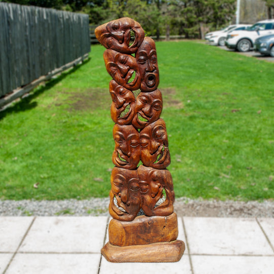 A unique wooden carved statue featuring many laughing faces