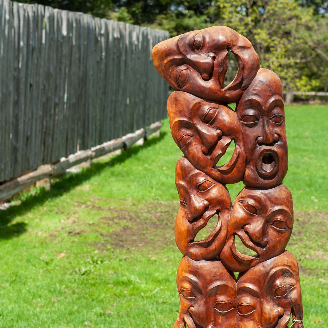 A unique wooden carved statue featuring many laughing faces