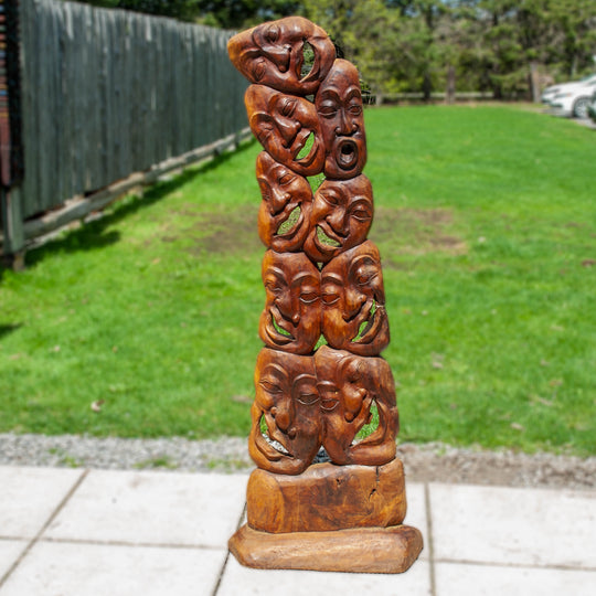 A unique wooden carved statue featuring many laughing faces