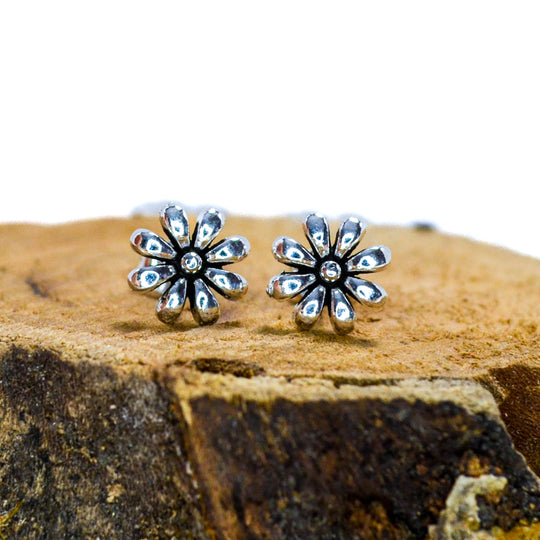 Small silver floral studs sitting on wood