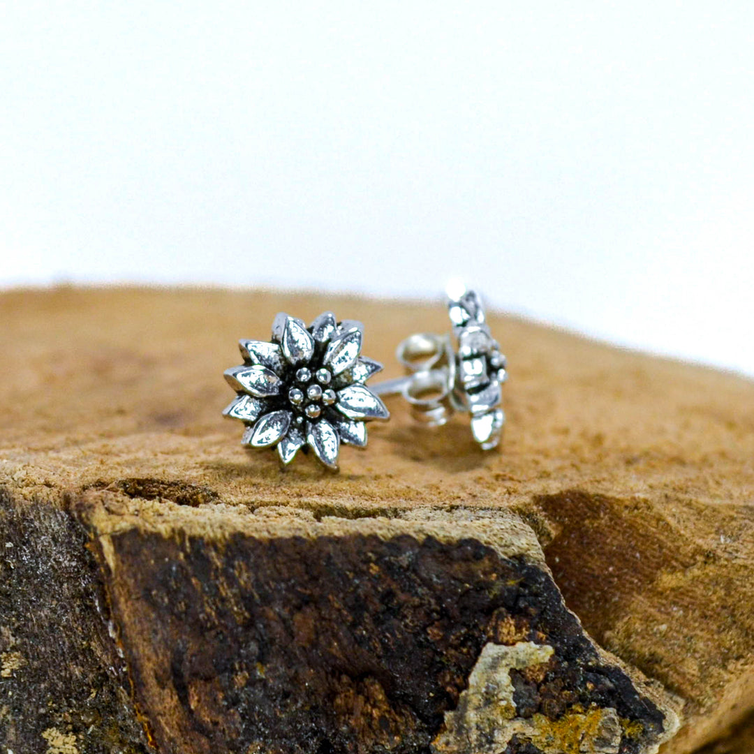 Small silver floral studs sitting on wood