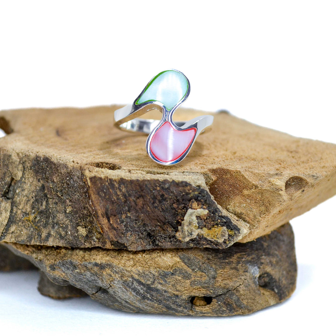 Ying-Yang design with green and red rainbow inlaid pieces silver ring sitting on piece of wood