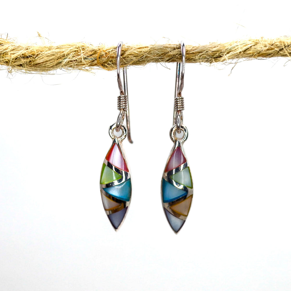 Rainbow coloured silver almond stud earrings on a piece of wood
