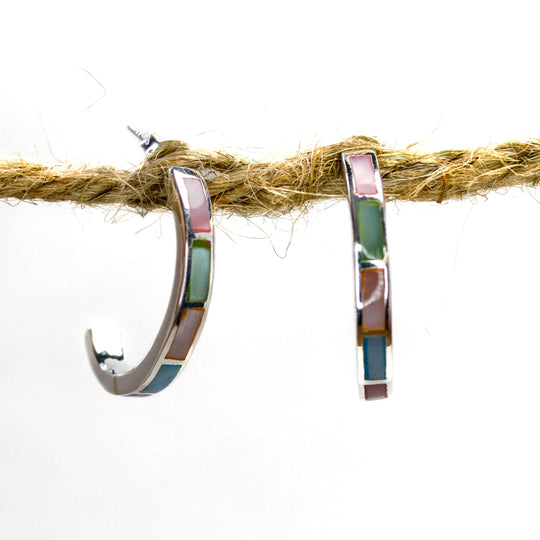 Rainbow coloured silver half circle stud earrings on a piece of wood