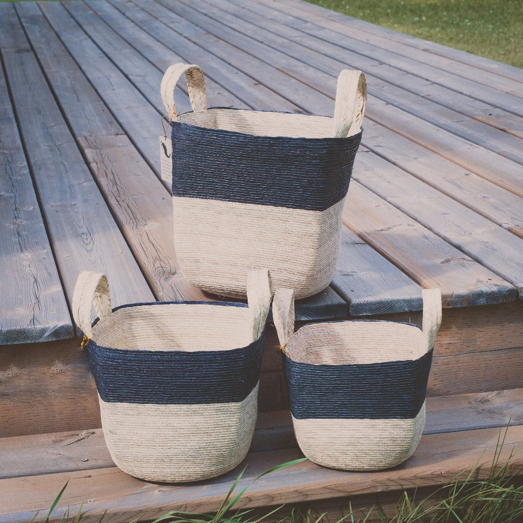 Natural woven baskets, three sizes on a wooden deck