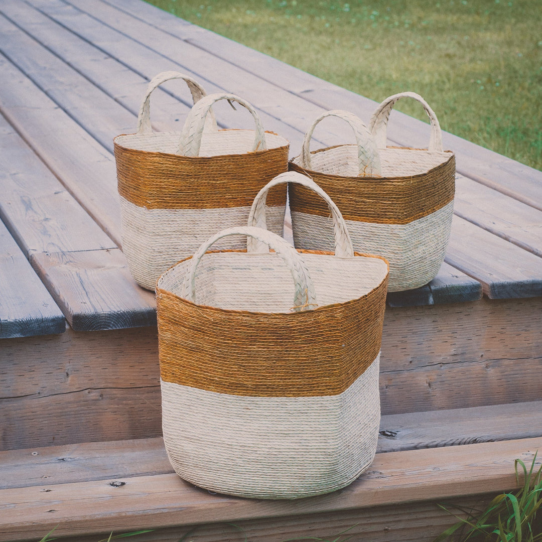 Natural woven baskets, three sizes on a wooden deck