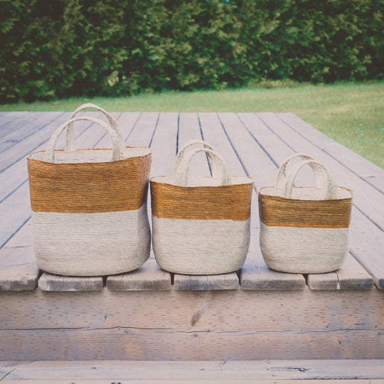 Natural woven baskets, three sizes on a wooden deck
