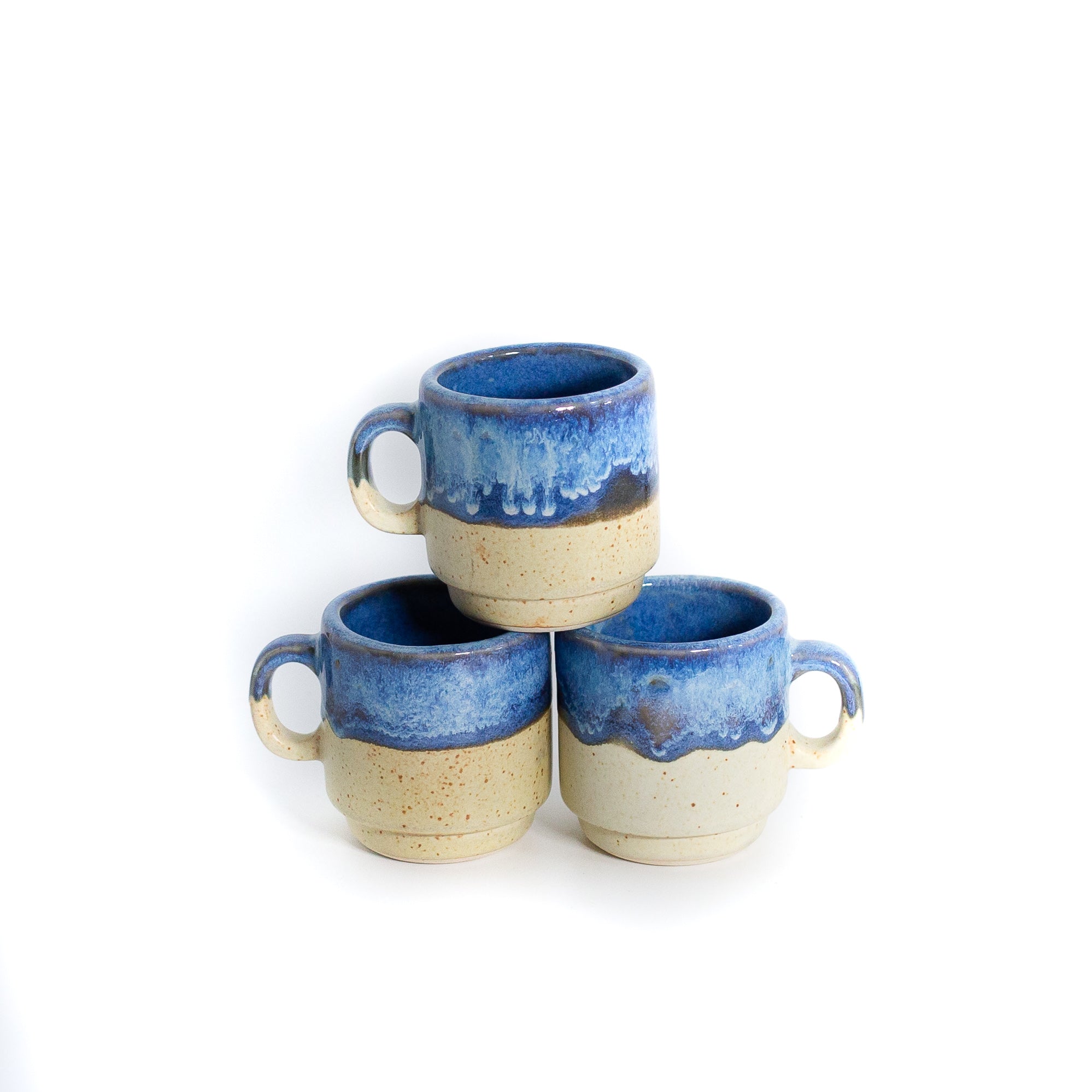 Small blue and cream coffee mugs stacked on white background