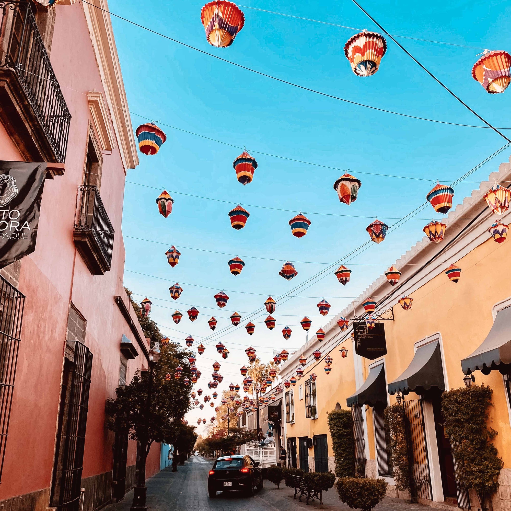 paper lanterns hang over a quiet street in mexico