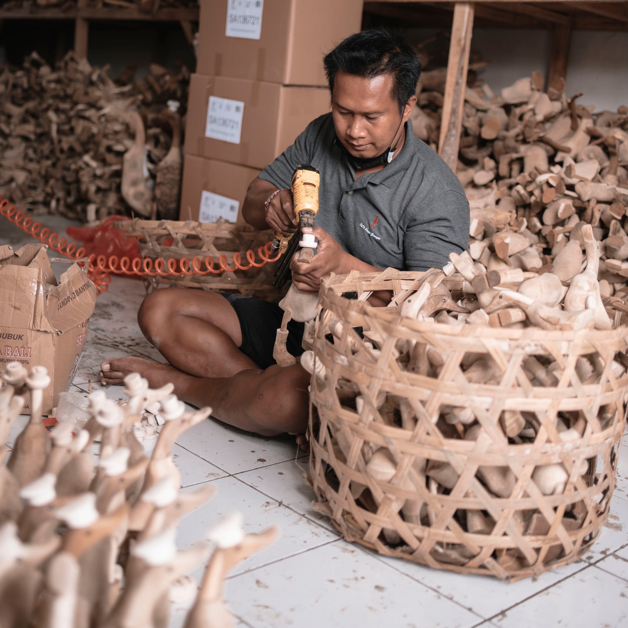 artisan makes wooden duck next to basket of ducks in his workshop