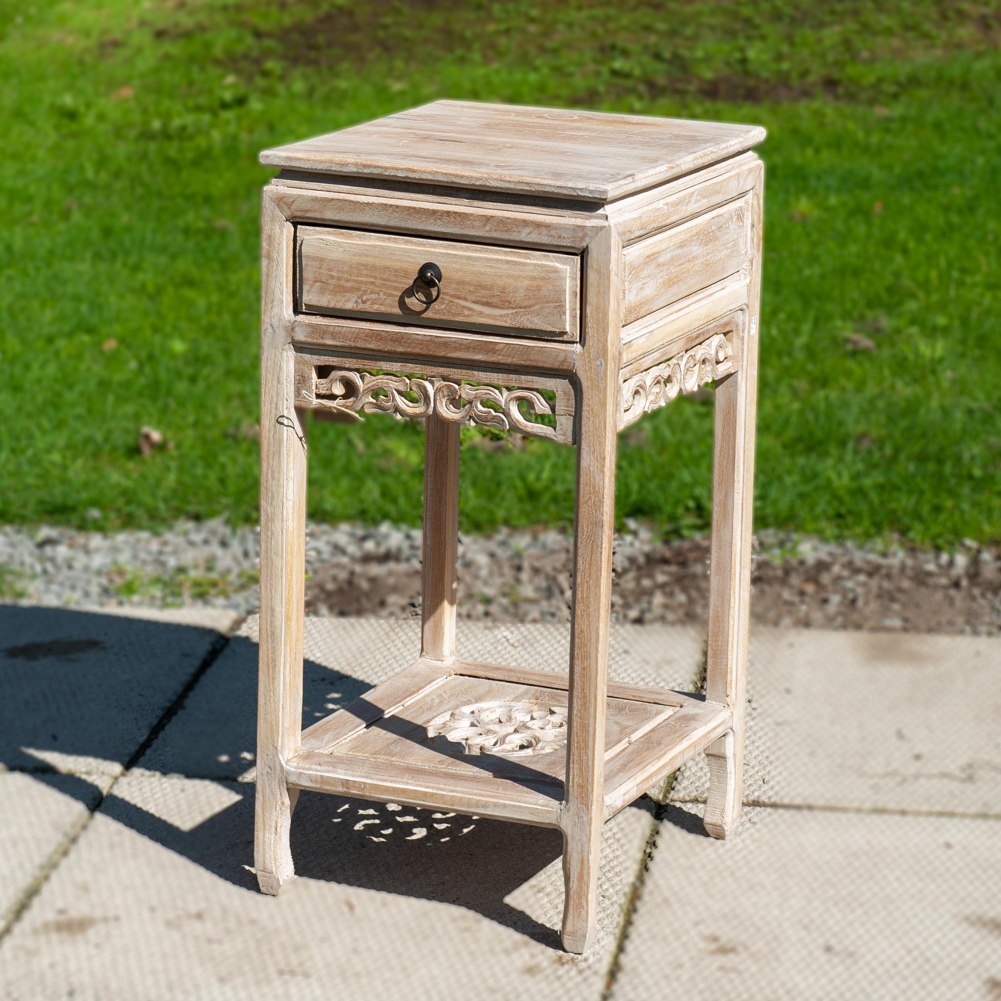 A white side table with ornate carvings and a single drawer