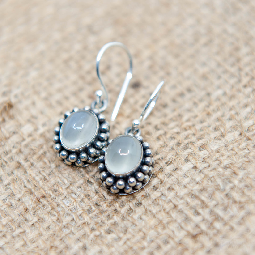 Boucles d'oreilles pendantes en pierre de lune blanche dans un sertissage floral
