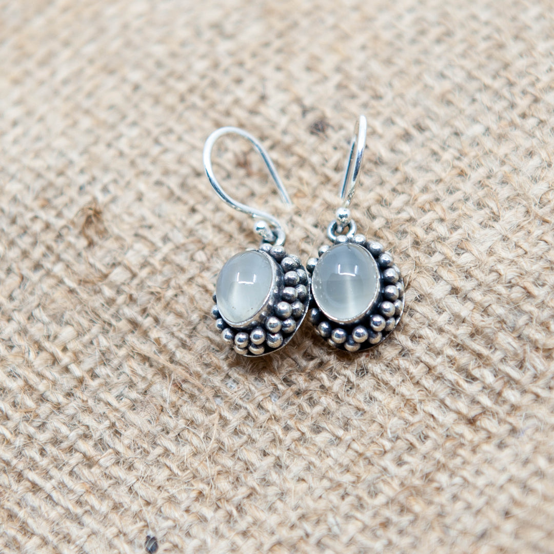 Boucles d'oreilles pendantes en pierre de lune blanche dans un sertissage floral