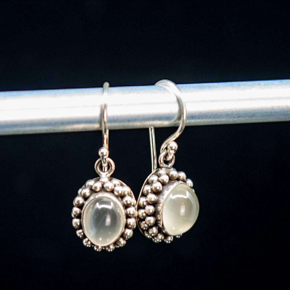 Boucles d'oreilles pendantes en pierre de lune blanche dans un sertissage floral