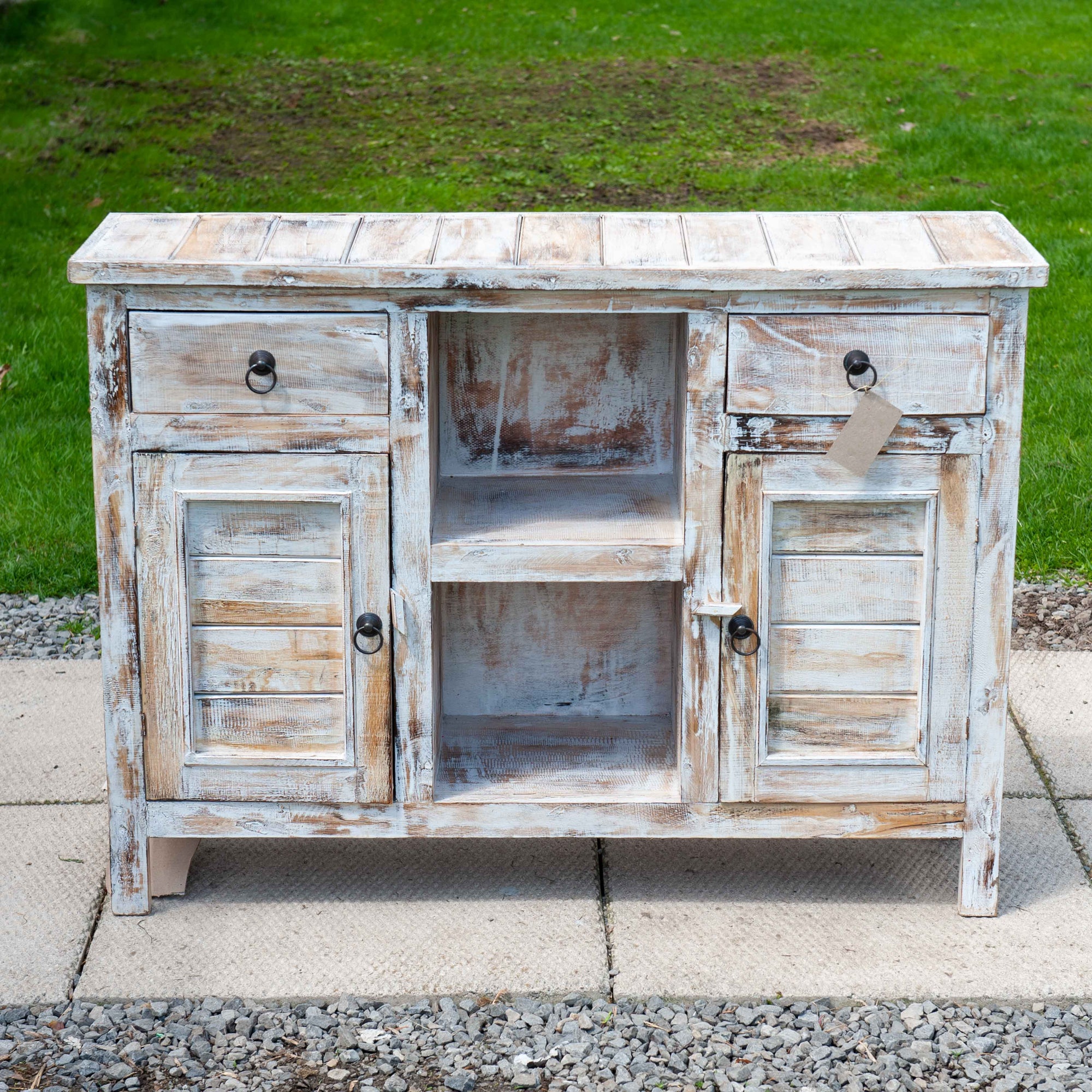 A medium size wooden cabinet in distressed white with 2 doors and storage shelves