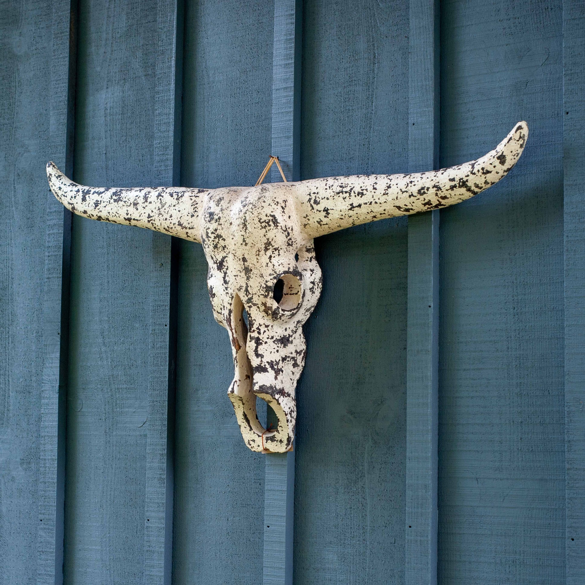 White textured cow skull carved from wood on blue barnboard 