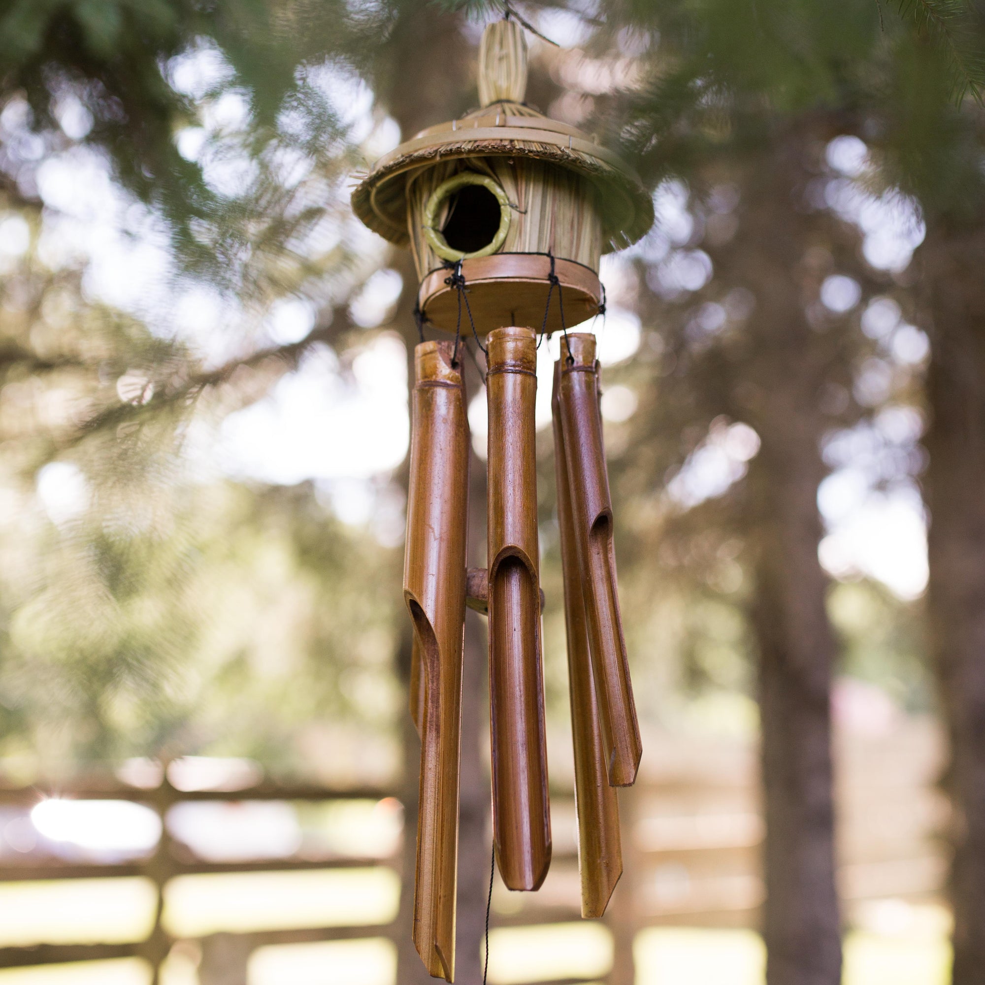 Photo of windchimes with a small grass bird house on top
