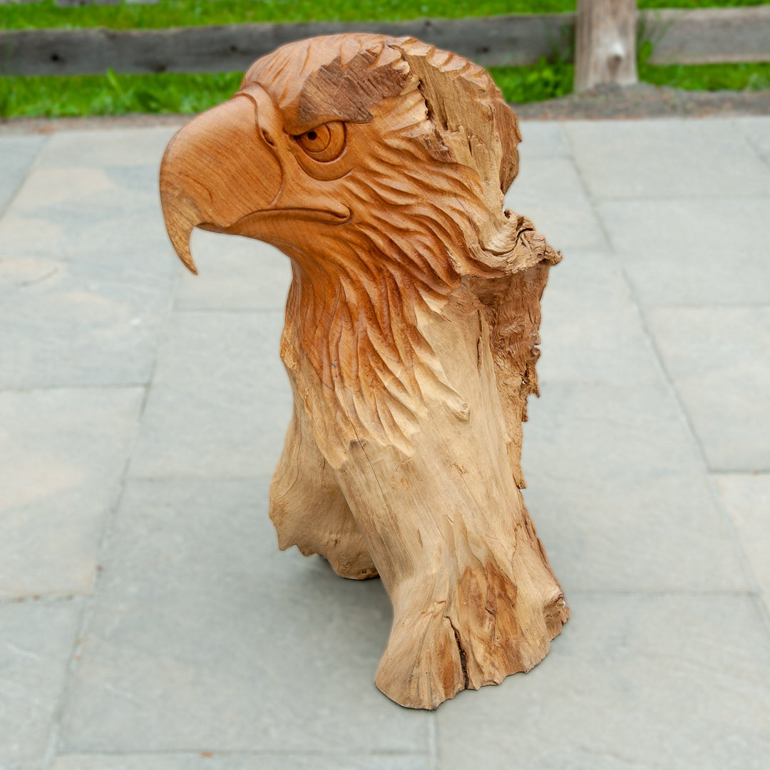An intricately carved teak wooden eagle sculpture stands majestically. 