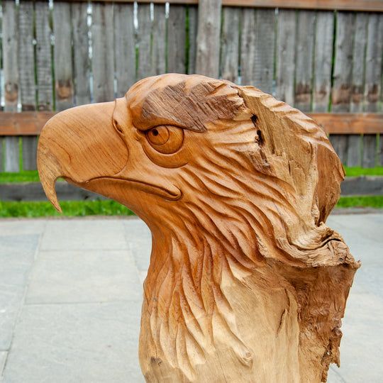An intricately carved teak wooden eagle sculpture stands majestically. 