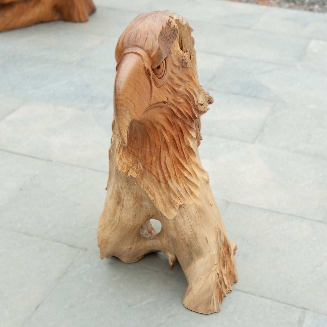 An intricately carved teak wooden eagle sculpture stands majestically. 