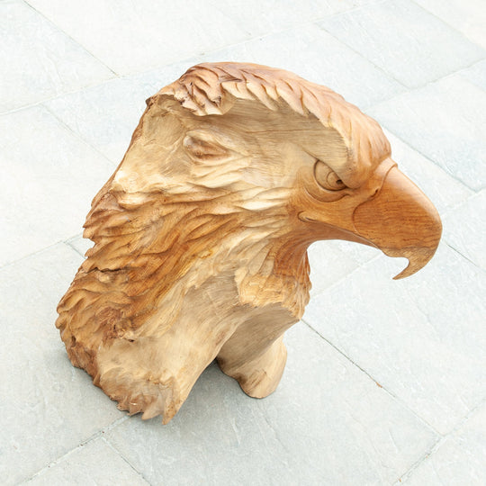An intricately carved teak wooden eagle sculpture stands majestically. 