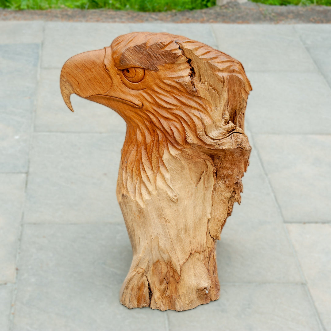 An intricately carved teak wooden eagle sculpture stands majestically. 