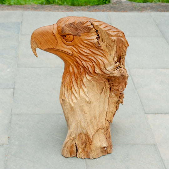 An intricately carved teak wooden eagle sculpture stands majestically. 