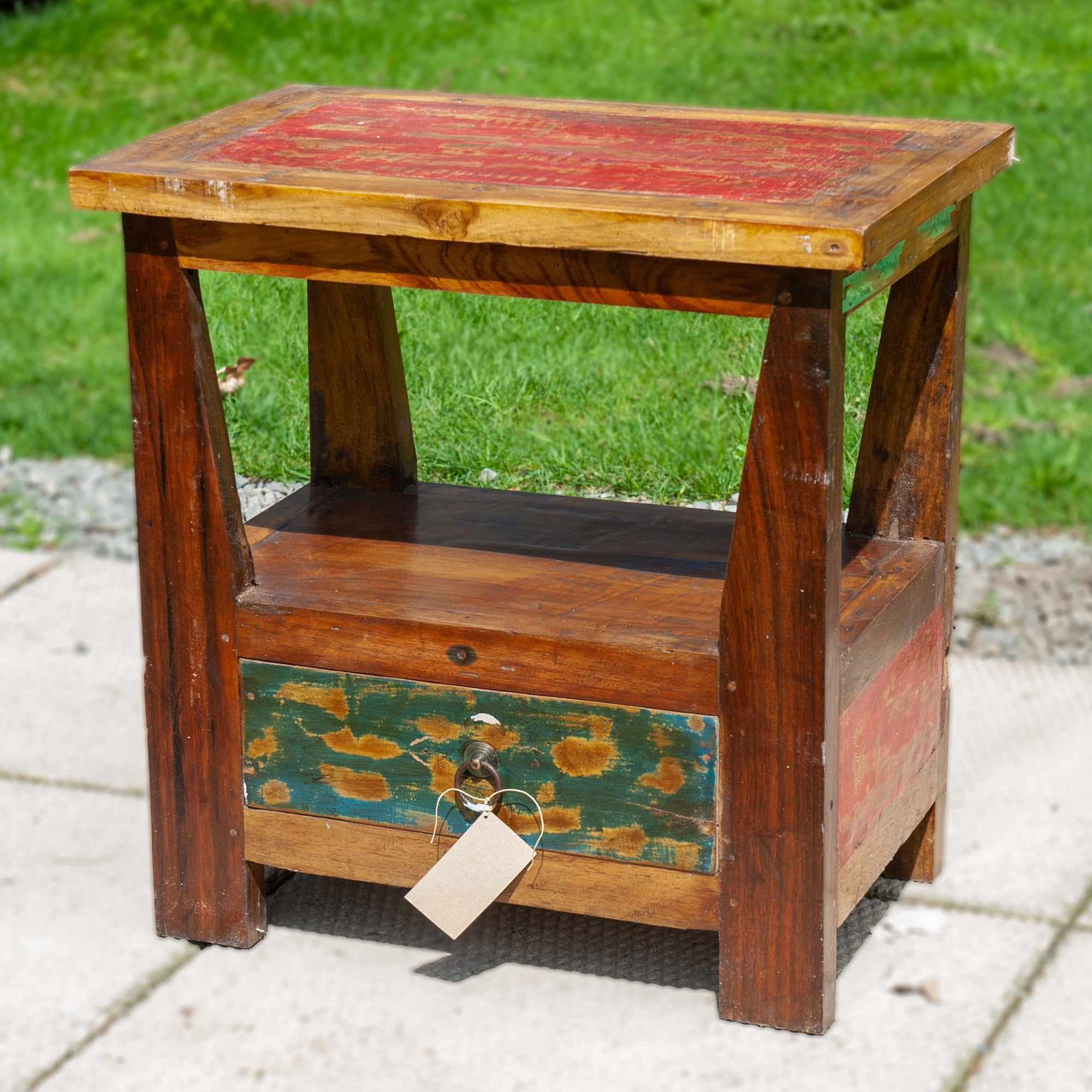 A funky reclaimed side table with open shelf and drawer and distressed red accent paint