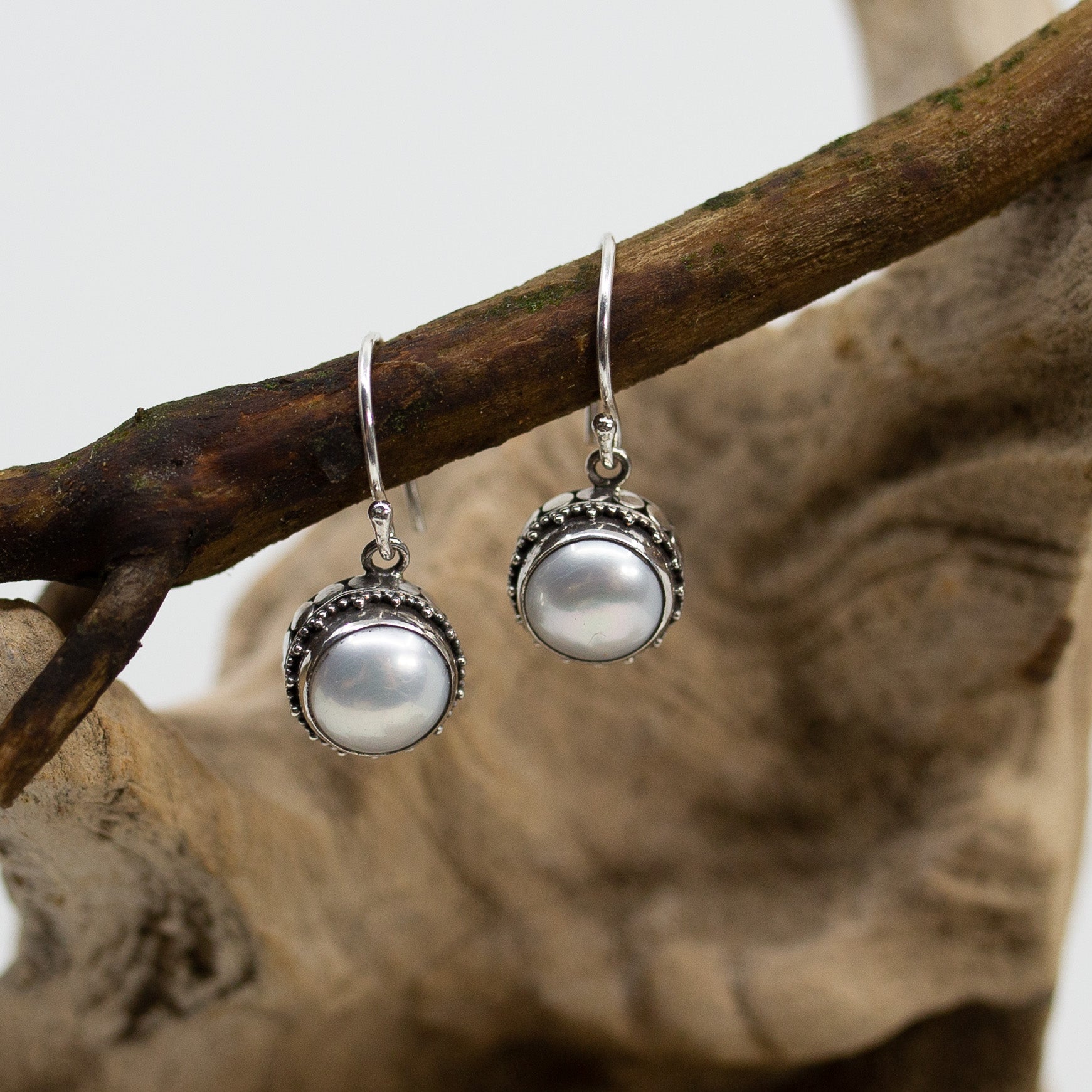Bali Dot & Swirl Pearl Dangle Earrings on wood