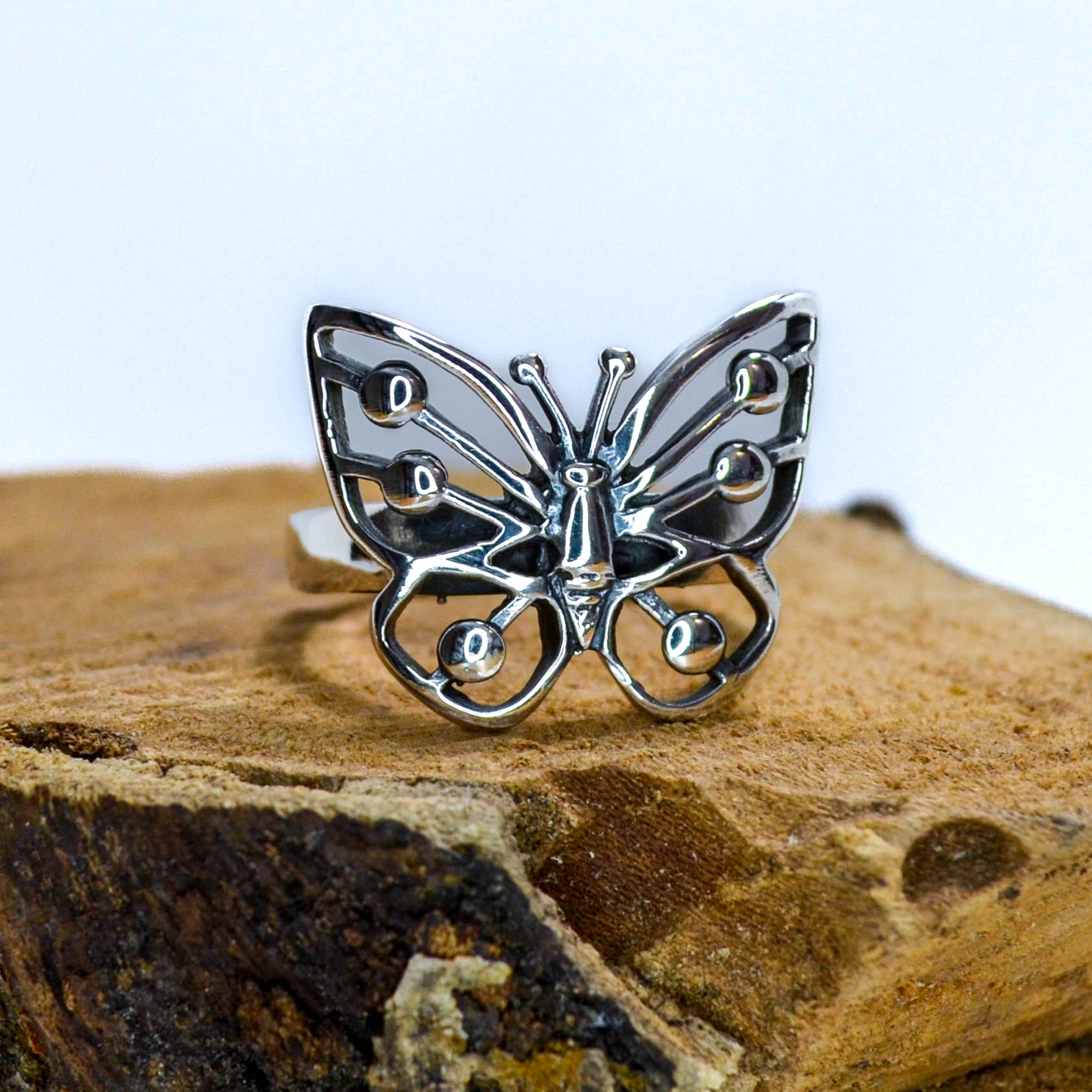 Silver Ring with Butterfly Design sitting on wood