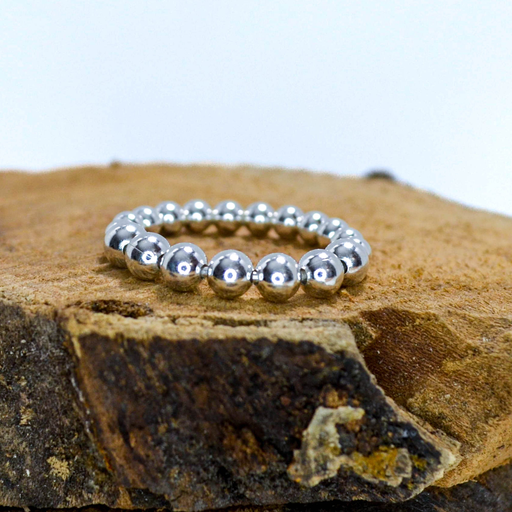 Ring made of small silver balls sitting on a piece of wood