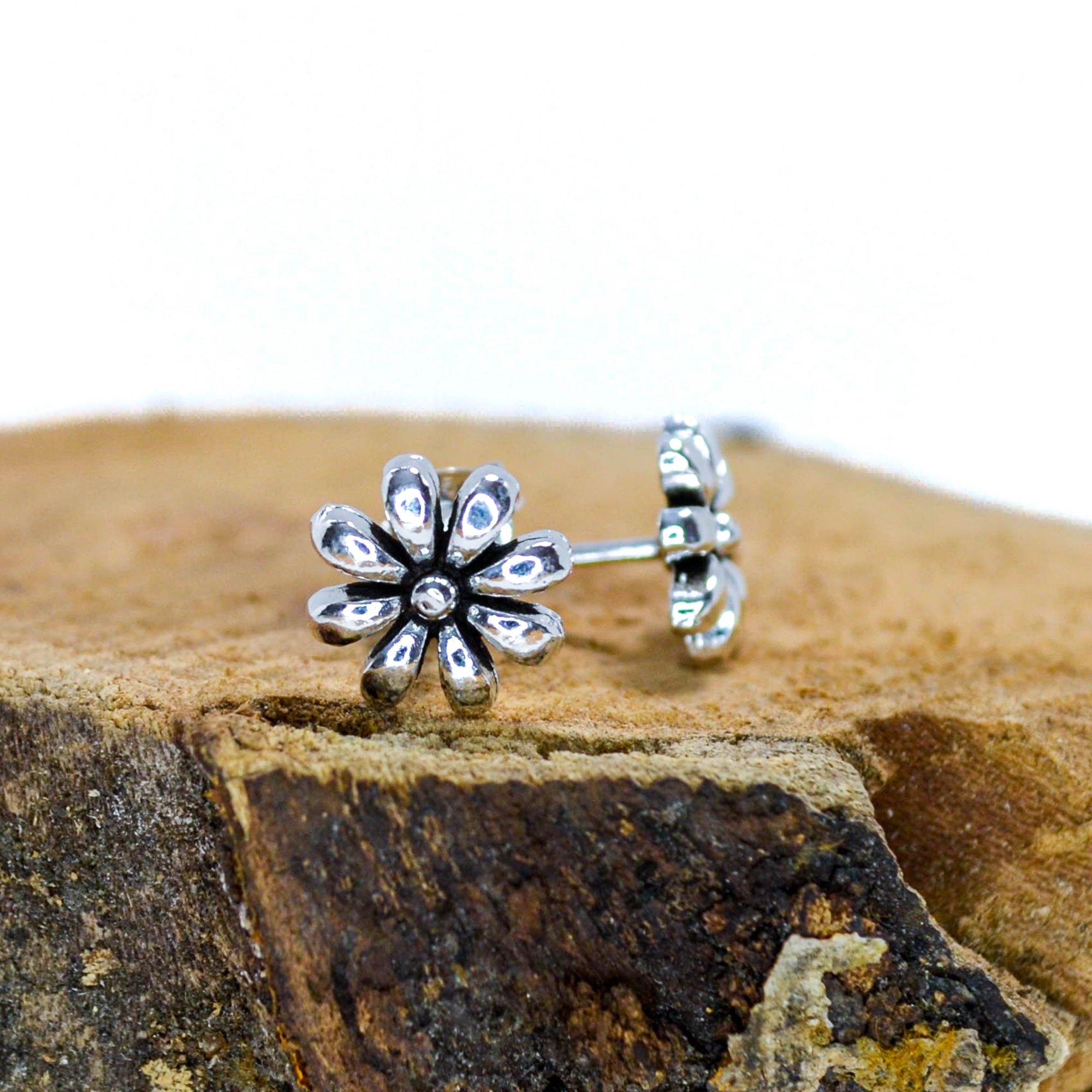 Small silver floral studs sitting on wood