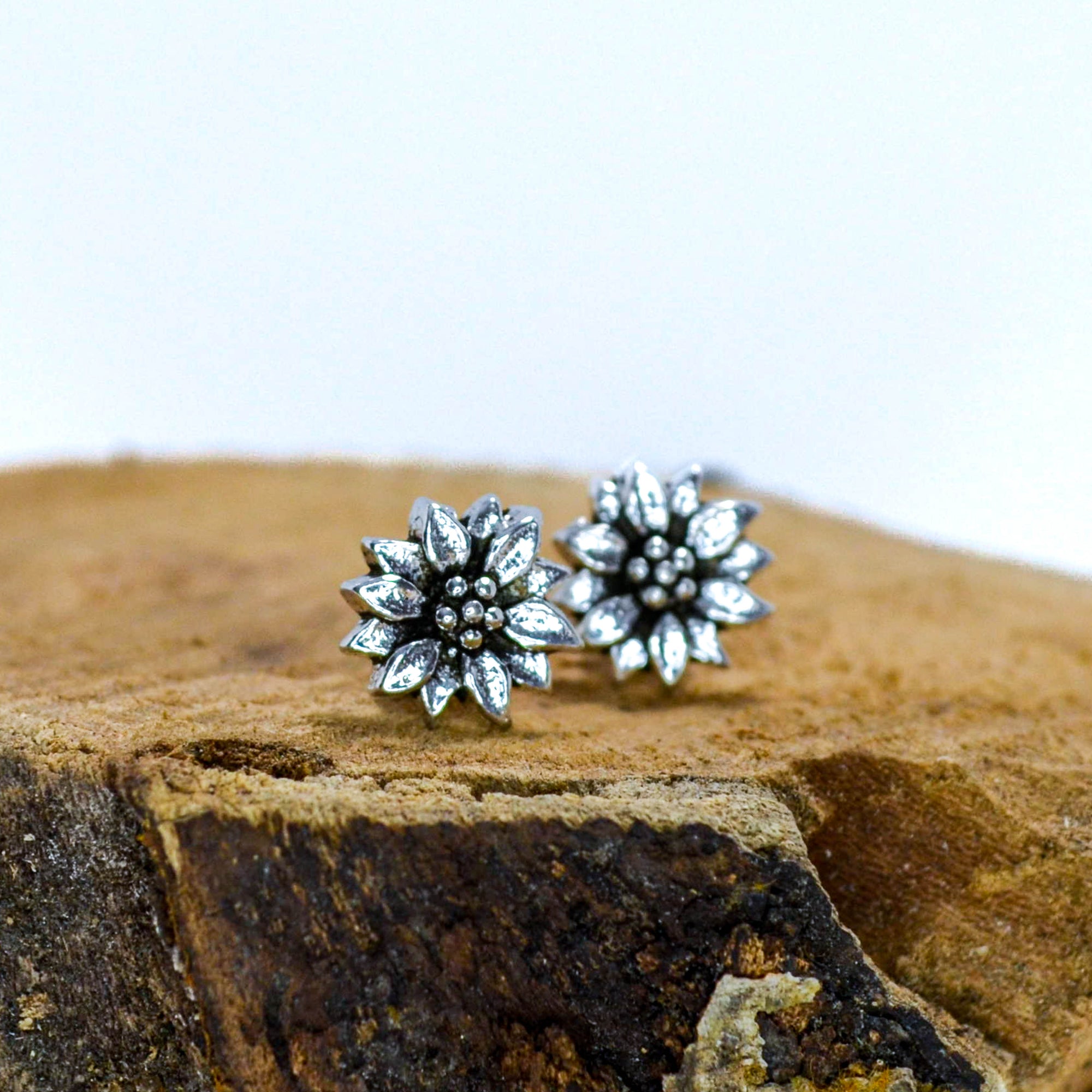 Small silver floral studs sitting on wood