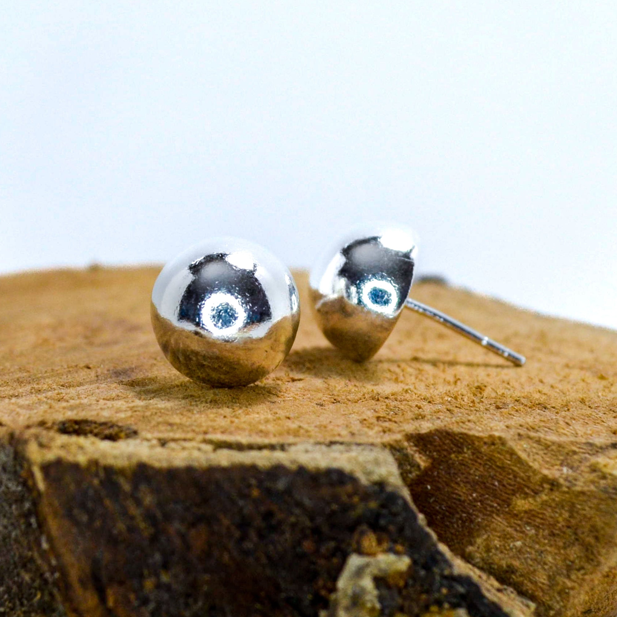 Small half sphere silver studs sitting on a piece of wood