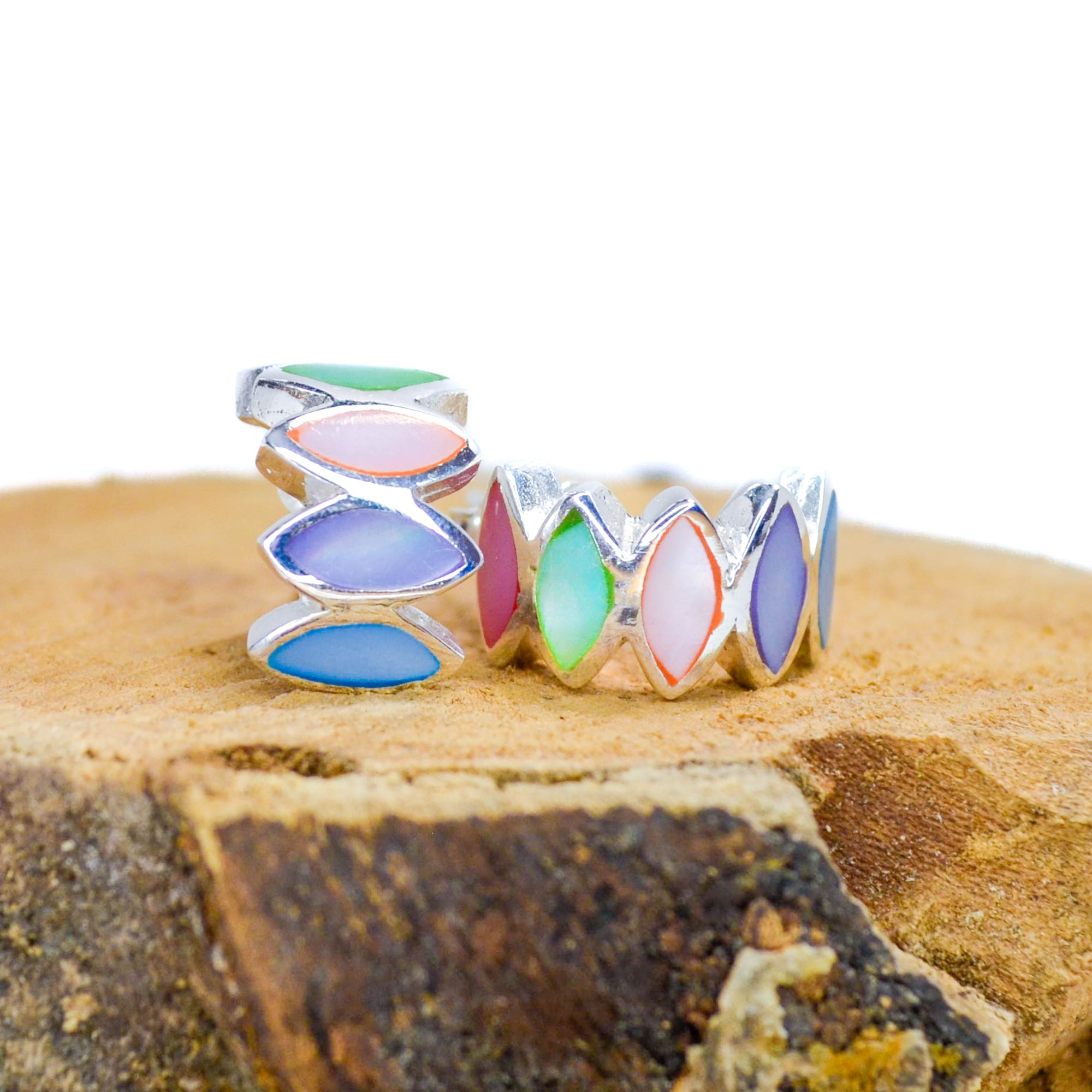 Rainbow coloured silver abstract half crown shape, stud earrings on a piece of wood