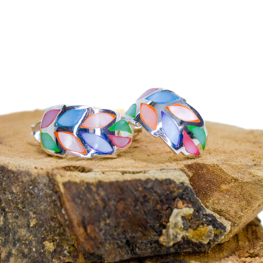 Rainbow coloured silver leaf stud earrings on a piece of wood